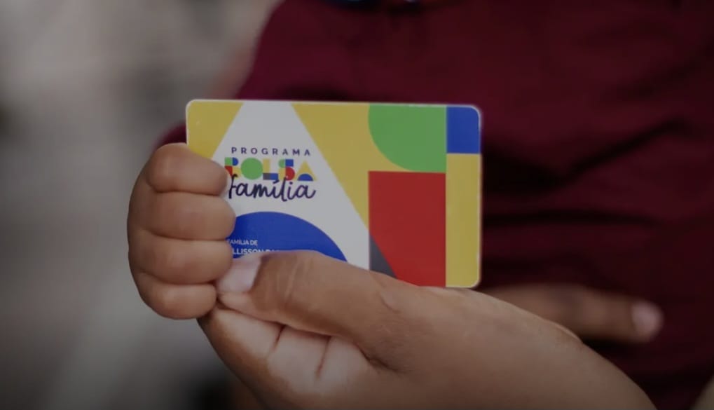 Mãos segurando um cartão do Bolsa Família